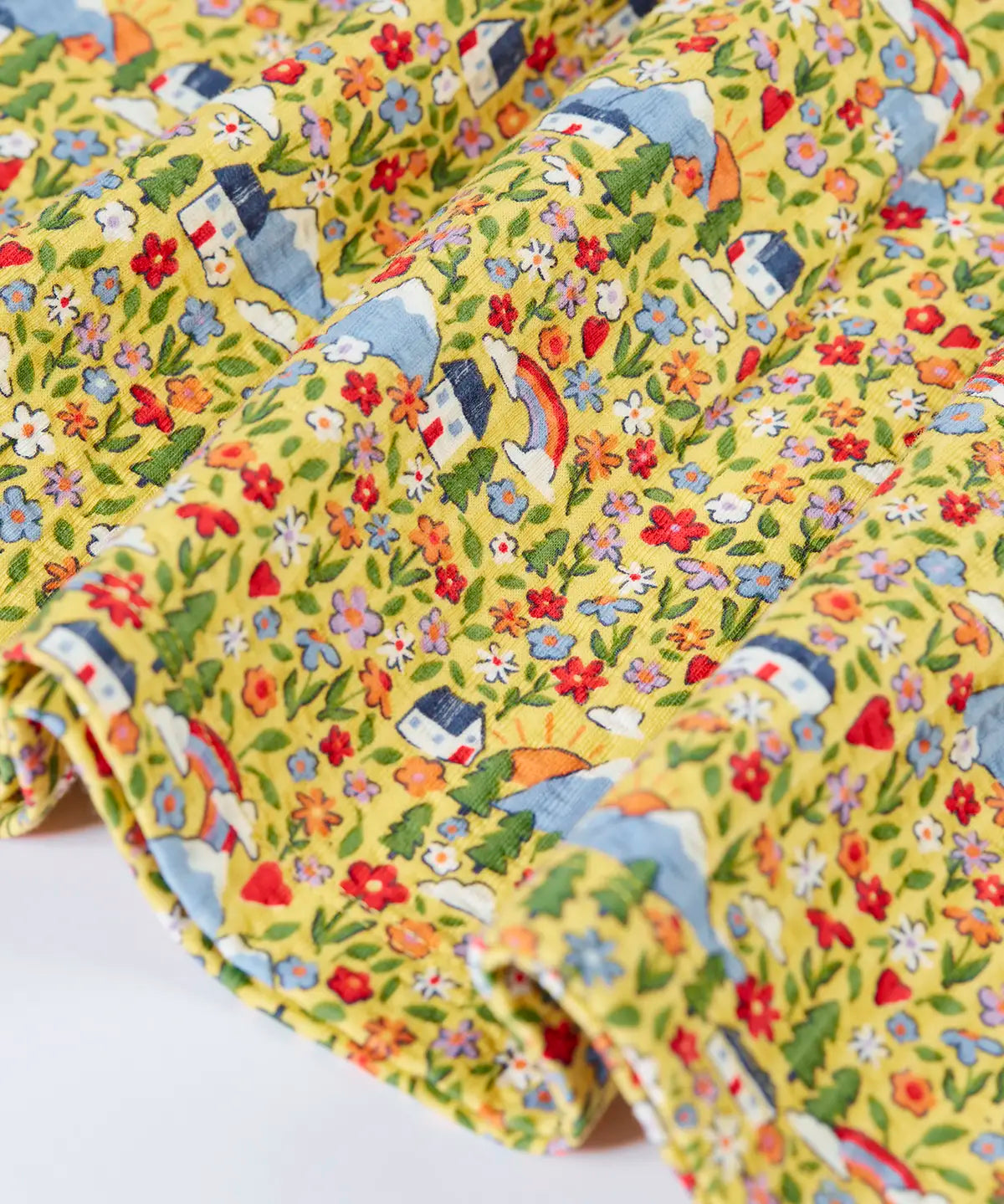 Close up of the hemline on the Frugi Izzie organic cotton jersey dress with highland houses print on a yellow background. 