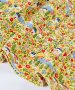 Close up of the hemline on the Frugi Izzie organic cotton jersey dress with highland houses print on a yellow background. 