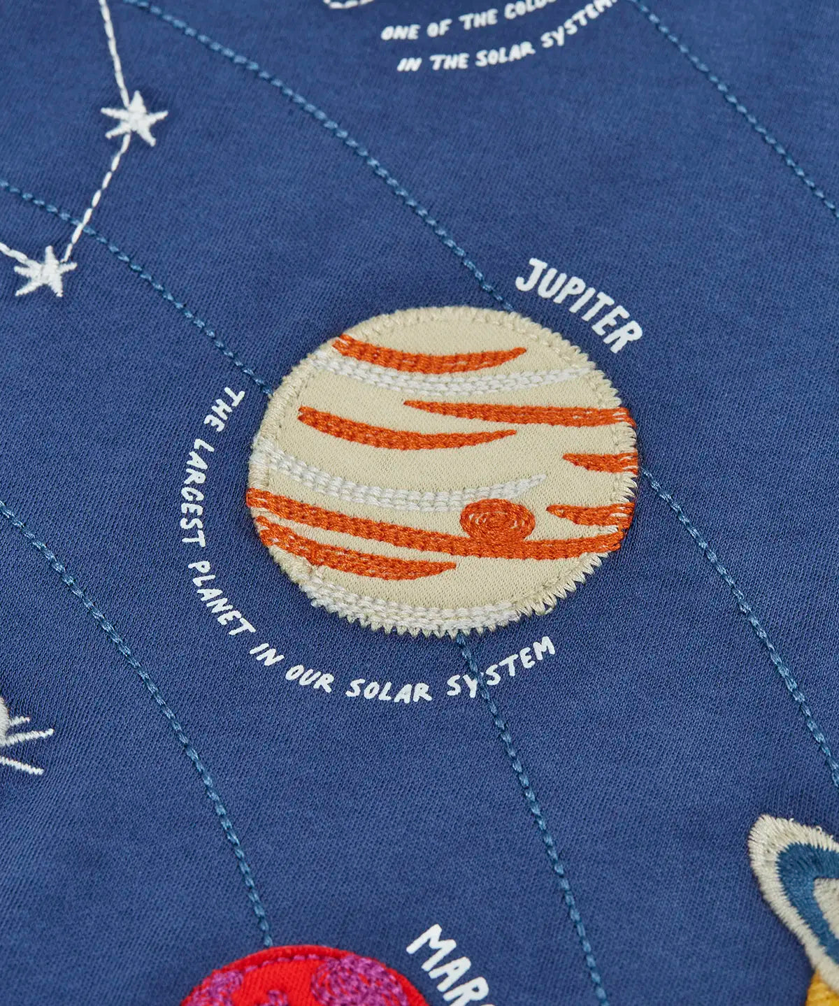 Close up of the Jupiter planet applique on the front of the Frugi Jake long sleeved applique top in navy blue.
