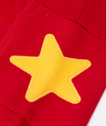 Close up of the yellow star applique on the side pocket of the Frugi journey joggers in scarlet red .