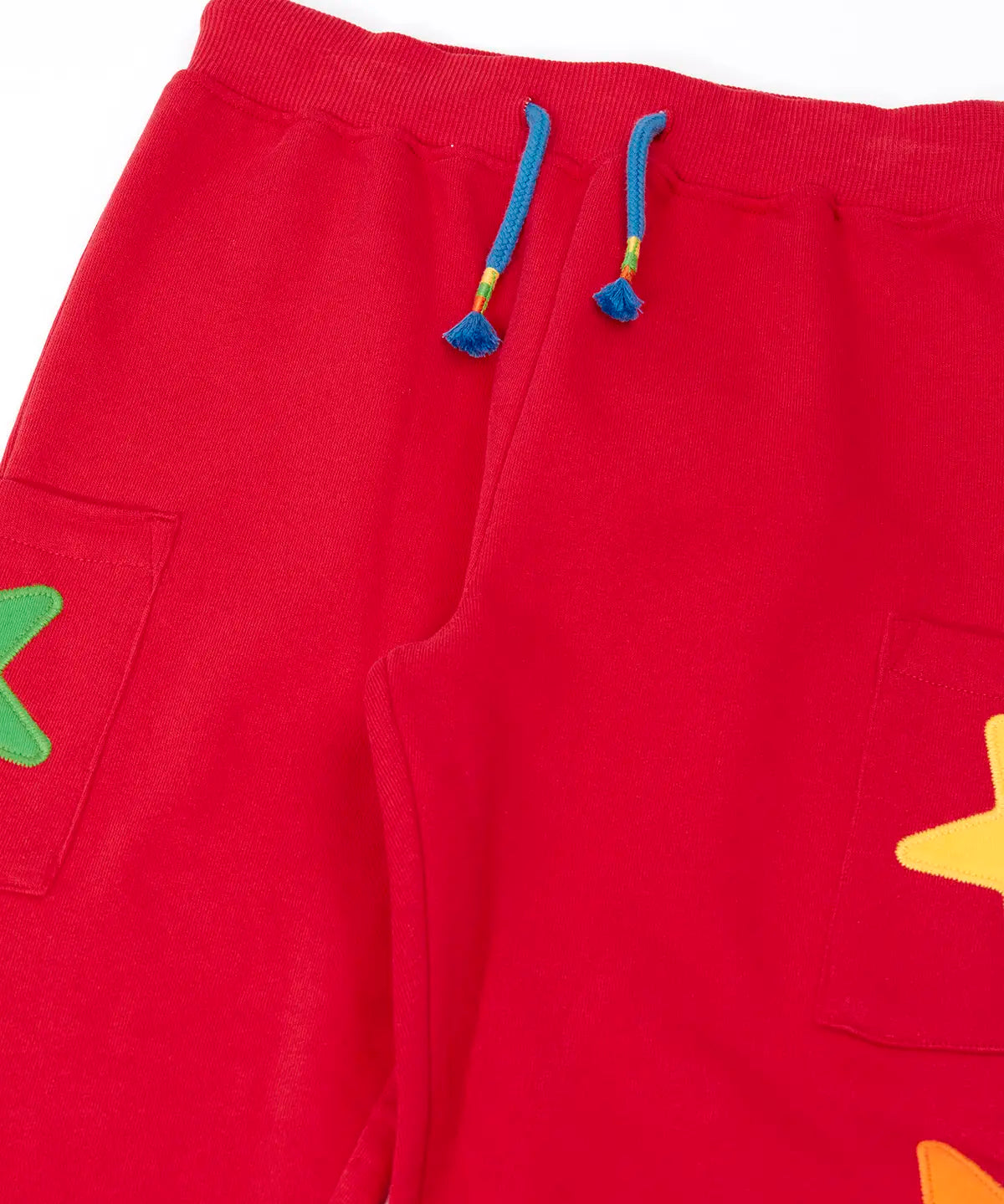 Close up of the front of the Frugi journey joggers in scarlet red with three stars appliques on each side.