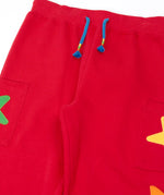 Close up of the front of the Frugi journey joggers in scarlet red with three stars appliques on each side.