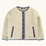 A cream-colored sherpa jacket with colorful floral patterned trim along the front placket, pocket openings, and collar.