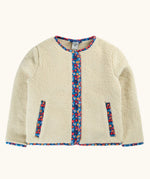 A cream-colored sherpa jacket with colorful floral patterned trim along the front placket, pocket openings, and collar.