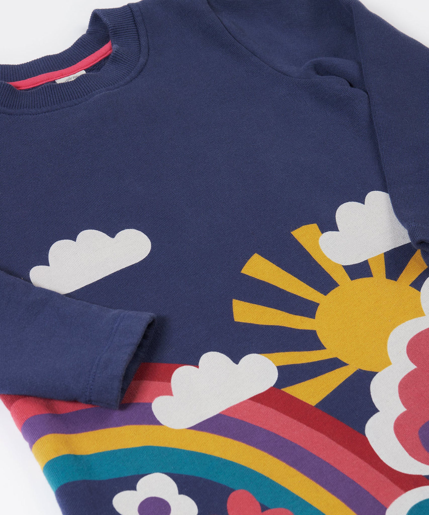 A close up of the Frugi kids kari dress in navy/rainbow showing the sleeve and woodland theme print detail on organic cotton fabric.