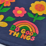 Close up of the rainbow do good things slogan design on the front of the Frugi Kari long sleeved dress in navy.
