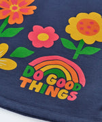 Close up of the rainbow do good things slogan design on the front of the Frugi Kari long sleeved dress in navy.