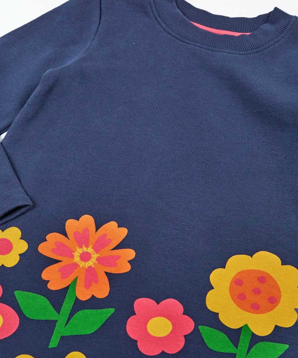 Close up of the Frugi Kari long sleeved dress in navy with flowers and do good things rainbow slogans along the hemline.