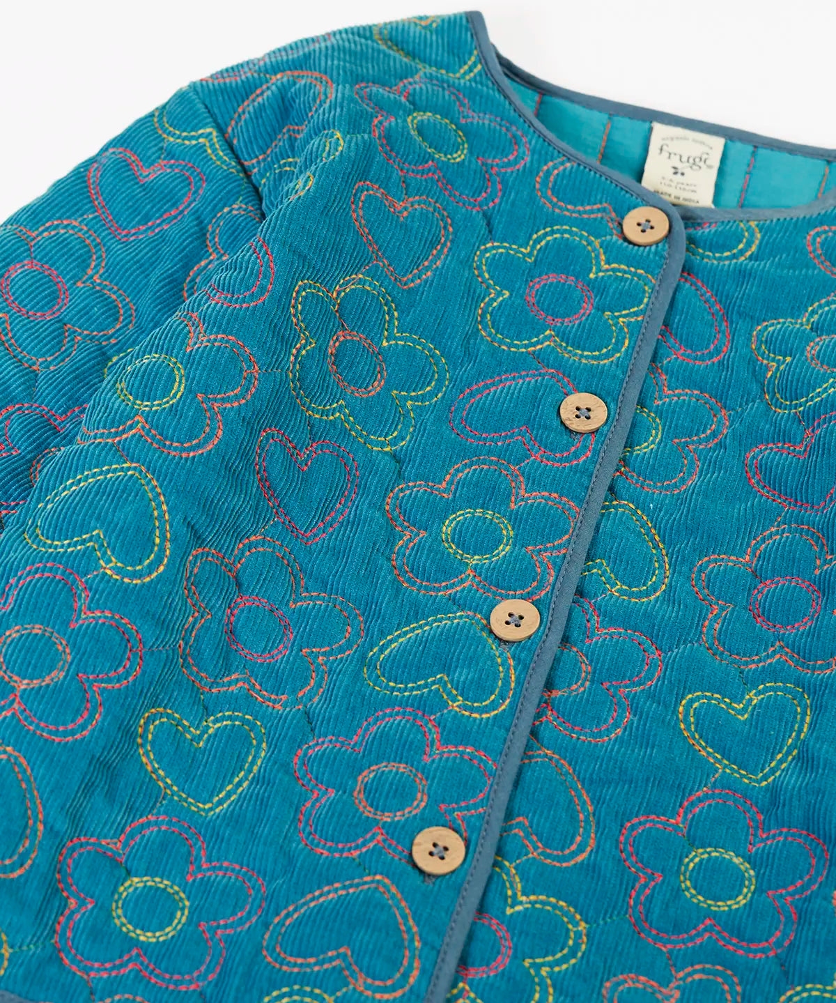 Close up of the button up closure on the front of the Frugi Katie quilted cord jacket in boat blue with floral pattern.