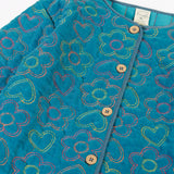 Close up of the button up closure on the front of the Frugi Katie quilted cord jacket in boat blue with floral pattern.