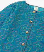 Close up of the button up closure on the front of the Frugi Katie quilted cord jacket in boat blue with floral pattern.