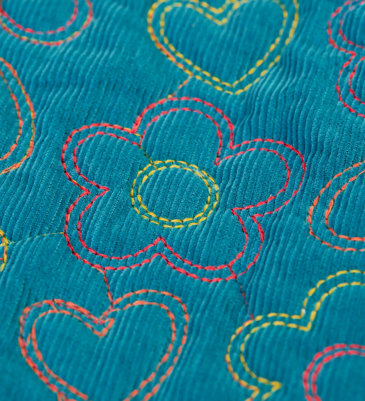 Close up of the floral embroidery on the Frugi Katie quilted cord jacket in boat blue. Flowers and hearts in various colours.