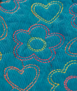 Close up of the floral embroidery on the Frugi Katie quilted cord jacket in boat blue. Flowers and hearts in various colours.