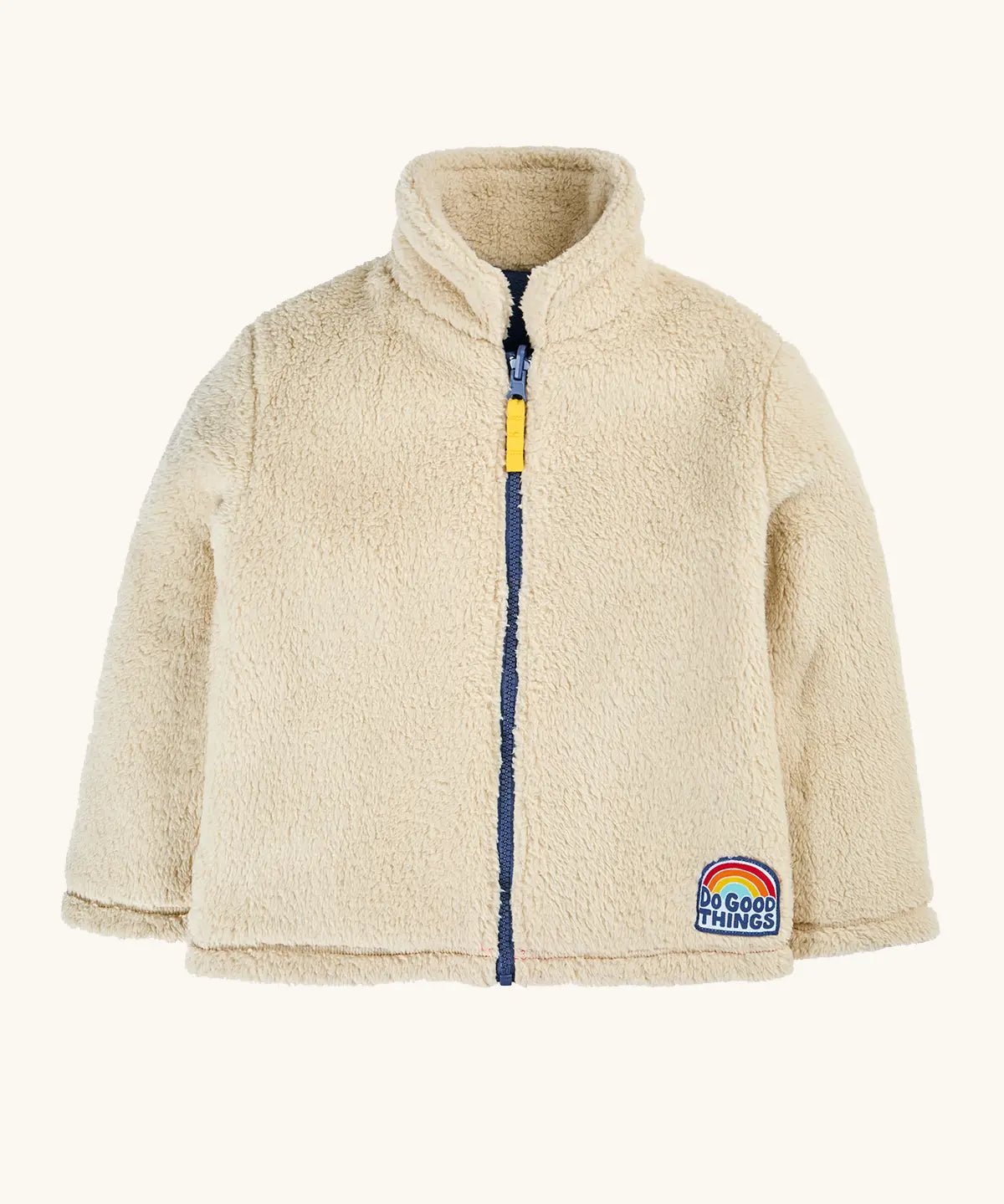 A cream-colored sherpa fleece zip-up jacket with a navy blue zipper, a yellow pull tab, and a 'Do Good Things' rainbow patch on the lower left hem.