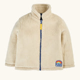 A cream-colored sherpa fleece zip-up jacket with a navy blue zipper, a yellow pull tab, and a 'Do Good Things' rainbow patch on the lower left hem.