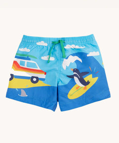 Frugi blue skies beach kids board shorts. A wrap around beach scene featuring a camper van and surfing penguin. 