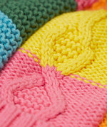 A close up of the Frugi kids cable knit rainbow check bobble hat. Showing the thick knit detail
