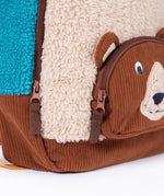 A close up of the  Frugi kids beary wild backpack. Showing the brown corduroy brown bear face pocket and zip detail. 