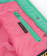 A close up of the Frugi kids 3 in 1 rambler coat in dragon/mushroom showing the hidden side pocket and bright turquoise zip detail on the inside of the coat on pink post consumer recycled polyester fabric