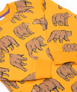 A close up of the Frugi kids Ethan printed sweater in beary wild. Showing the elasticated cuff detail on the arm on dark yellow organic cotton fabric.