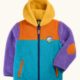 A frugi fleece hooded jacket with a color-blocked design in teal, orange, and purple, featuring a yellow sherpa-lined hood and an orange elbow patch. A circular 'navigate nature' logo is visible on the left chest.