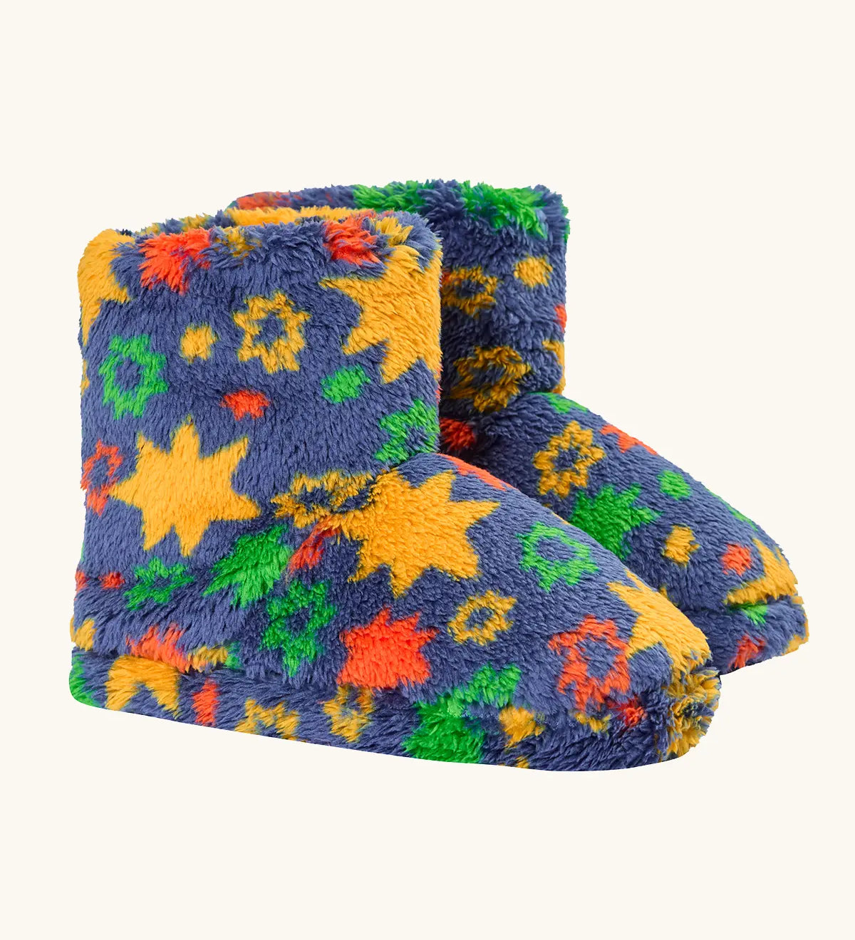 A pair of frugi plush, fuzzy slipper boots in a navy blue base with a colorful pattern of yellow stars, green and orange flowers, and red accents