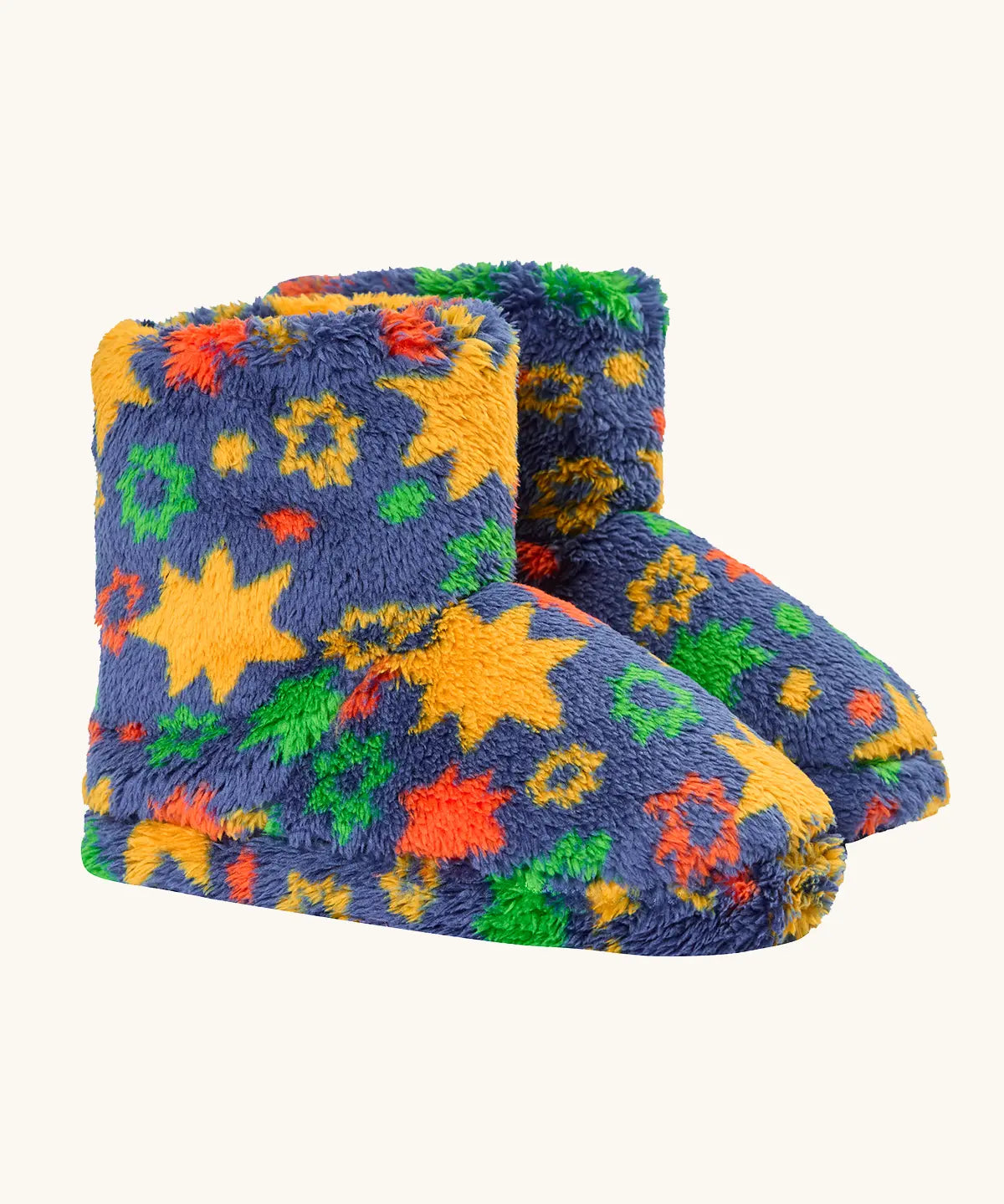 A pair of frugi plush, fuzzy slipper boots in a navy blue base with a colorful pattern of yellow stars, green and orange flowers, and red accents