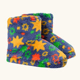 A pair of frugi plush, fuzzy slipper boots in a navy blue base with a colorful pattern of yellow stars, green and orange flowers, and red accents
