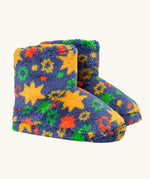 A pair of frugi plush, fuzzy slipper boots in a navy blue base with a colorful pattern of yellow stars, green and orange flowers, and red accents