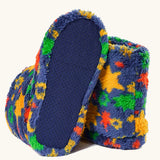 underneath of fuzzy slip-on slippers with a colorful star pattern on a blue base, shown on a light cream background. 
