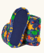 underneath of fuzzy slip-on slippers with a colorful star pattern on a blue base, shown on a light cream background. 