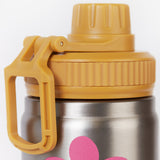 A close up of the Frugi kids Insulated bottle in fun flowers. Showing the yellow cap with loop detail. 