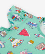 A close up of the Frugi kids lets bake Morwenna skater dress. Showing the different cakes, ice cream, puddings and short sleeve on light green organic cotton fabric