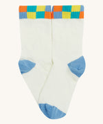 Close up of the Frugi white sunnie socks. Showing the multicoloured check design on the ankle cuff. Features a light blue heel and toe contrast panel on white organic cotton fabric