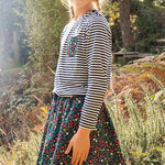 Girl stood in the woods wearing a striped top and the Frugi floral print maeve twill skirt