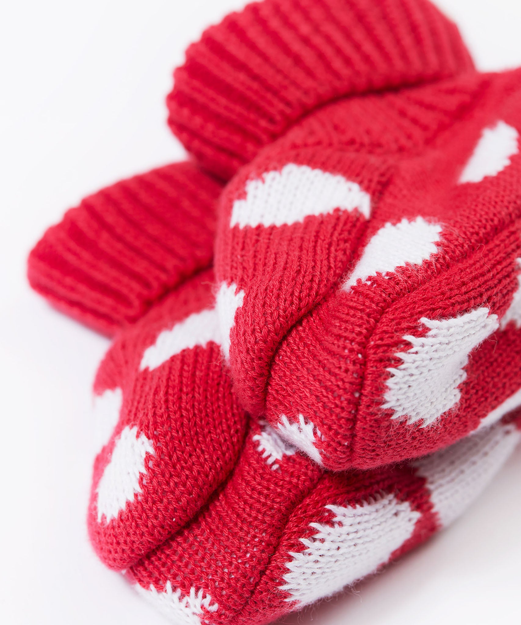 A close up of the Frugi kids noa knitted booties in red mushroom showing the red and white soft knit detail. 