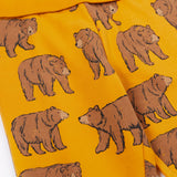 A close up of the Frugi kids beary wild parsnip joggers showing the bear print detail and turn up waist hem on dark yellow organic cotton fabric.