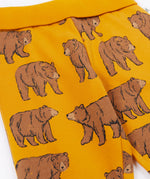 A close up of the Frugi kids beary wild parsnip joggers showing the bear print detail and turn up waist hem on dark yellow organic cotton fabric.