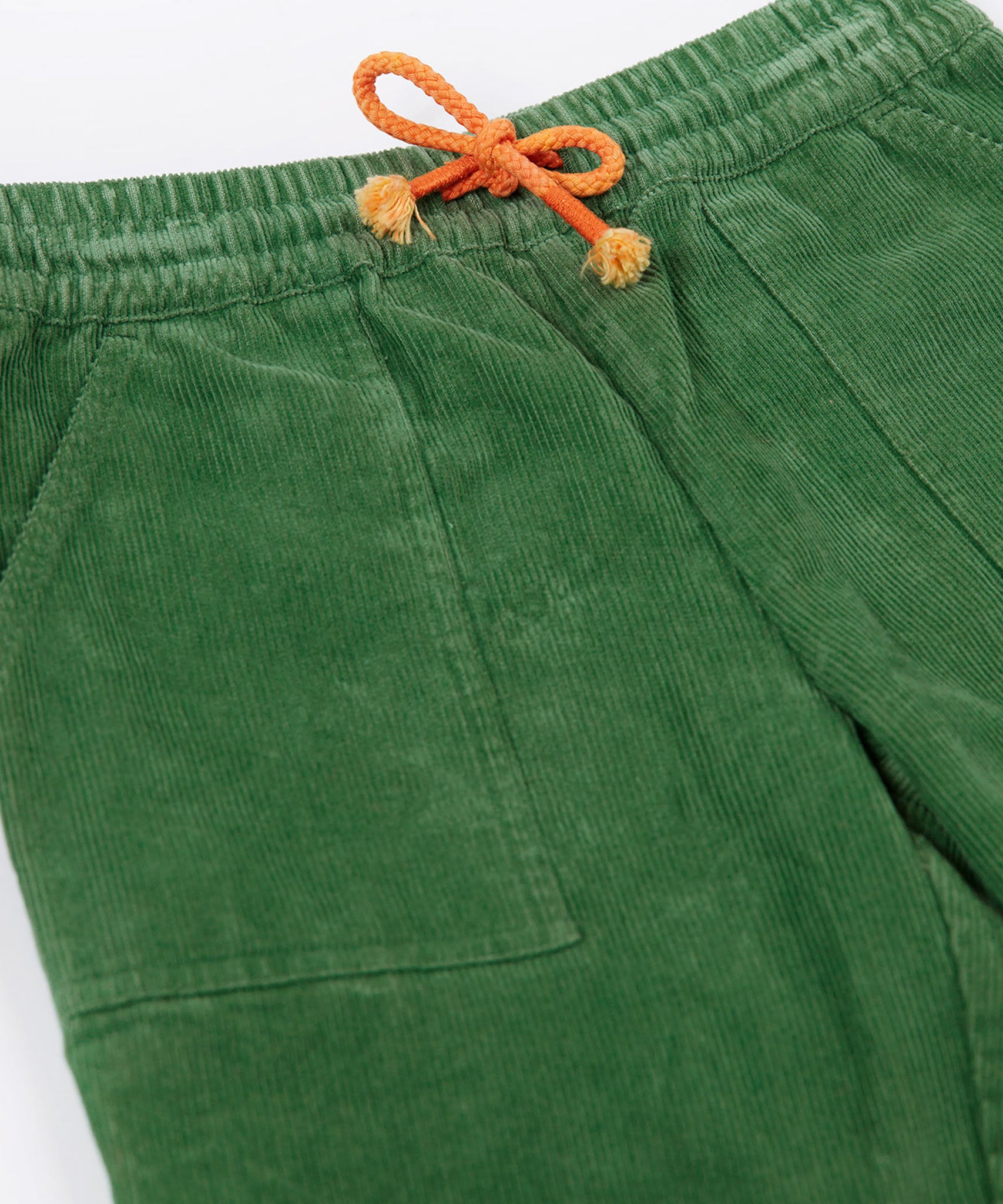 A close up of the waist band and pockets on the Frugi Kids' Organic Cotton Corduroy Trousers in a Holly Green colour.
