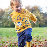 A little toddler boy wearing the Frugi organic cotton leopard knitted jumper and the Frugi organic cotton cord pull ups in Ink Blue.