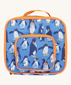 Frugi kids pack a lunch bag in penguin waddle. A blue lunch bag with multiple prints of penguins and orange trim. Features 2 compartments with zip fasteners and handy pink carry handle.