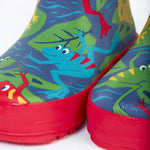 A close up of the bottom of the Frugi kids puddle buster wellington boots. Showing the the red trim and playful frog print detail on navy natural rubber material.