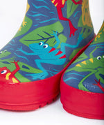 A close up of the bottom of the Frugi kids puddle buster wellington boots. Showing the the red trim and playful frog print detail on navy natural rubber material.