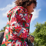 Child wearing Frugi waterproof puddle buster coat in pink purrfect ponies print showing the reflective strips on the wrist are of the arms. 