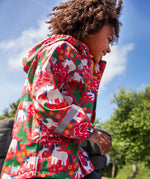 Child wearing Frugi waterproof puddle buster coat in pink purrfect ponies print showing the reflective strips on the wrist are of the arms. 