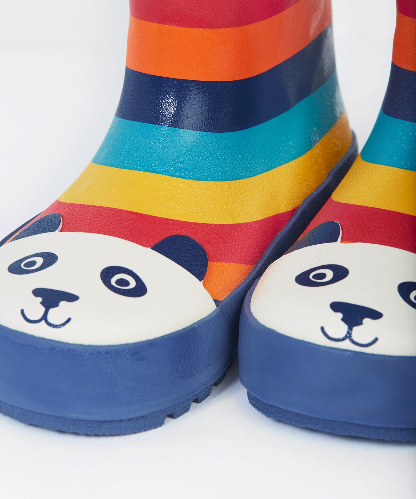 A close up of the bottom of the Frugi kids puddle buster wellington boots. Showing the the navy trim and playful panda print detail on multicoloured natural rubber material.
