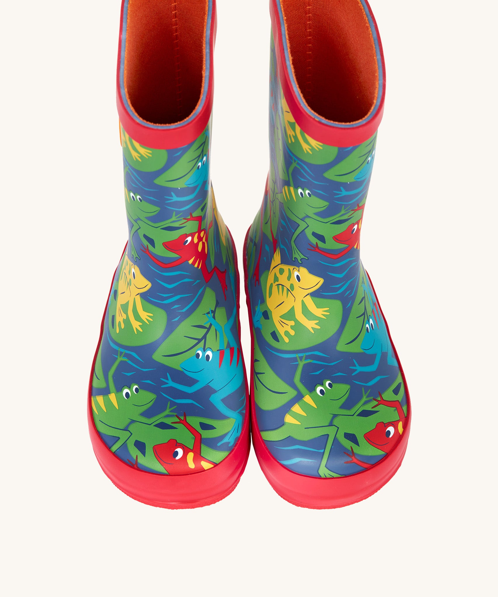 A top down view of the Frugi kids puddle buster wellington boots Showing the the red trim and playful frog print detail on navy natural rubber material. 