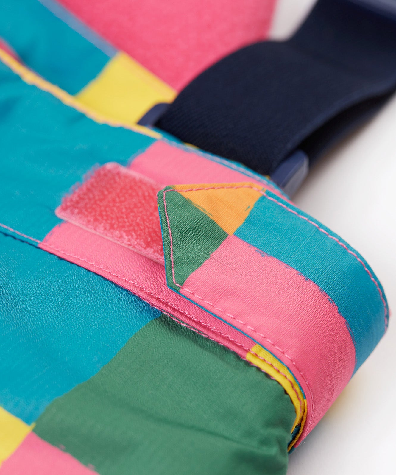 A close up of the Frugi penguin waddle snow and ski salopettes showing adjustable waist band detail on a bright check recycled polyester fabric