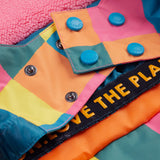 A close up of the Frugi kids snow and ski coat in rainbow check showing the snow skirt detail in matching rainbow check design and blue popper fasteners