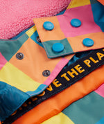 A close up of the Frugi kids snow and ski coat in rainbow check showing the snow skirt detail in matching rainbow check design and blue popper fasteners